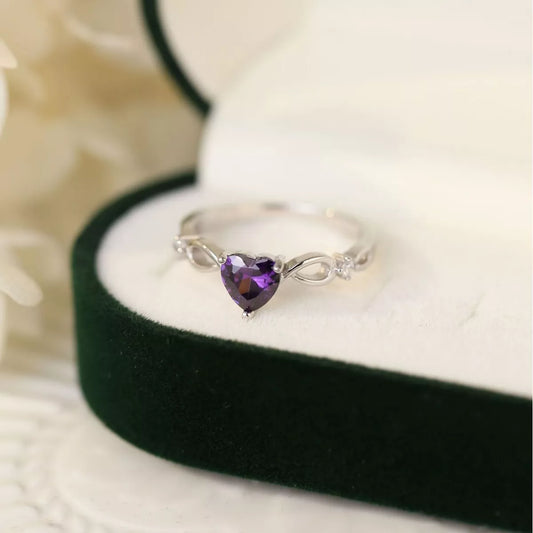 Silver ring with heart-shaped amethyst gemstone displayed in a green velvet box