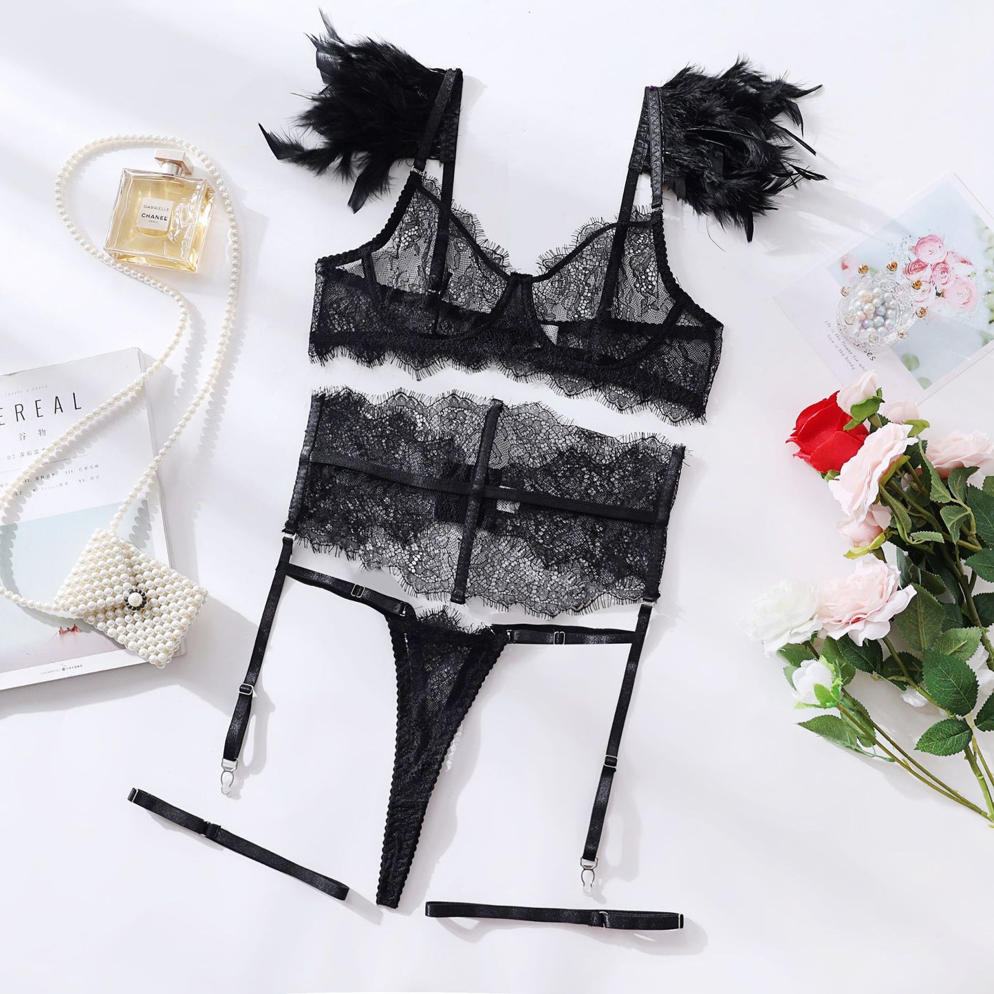 Flat lay of black lace lingerie set with garter straps and floral accessories