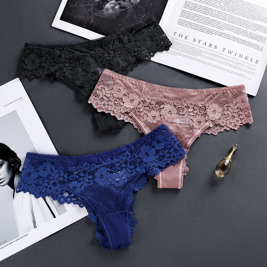 Flat lay of lace panties in black, rose pink, and navy blue on dark background