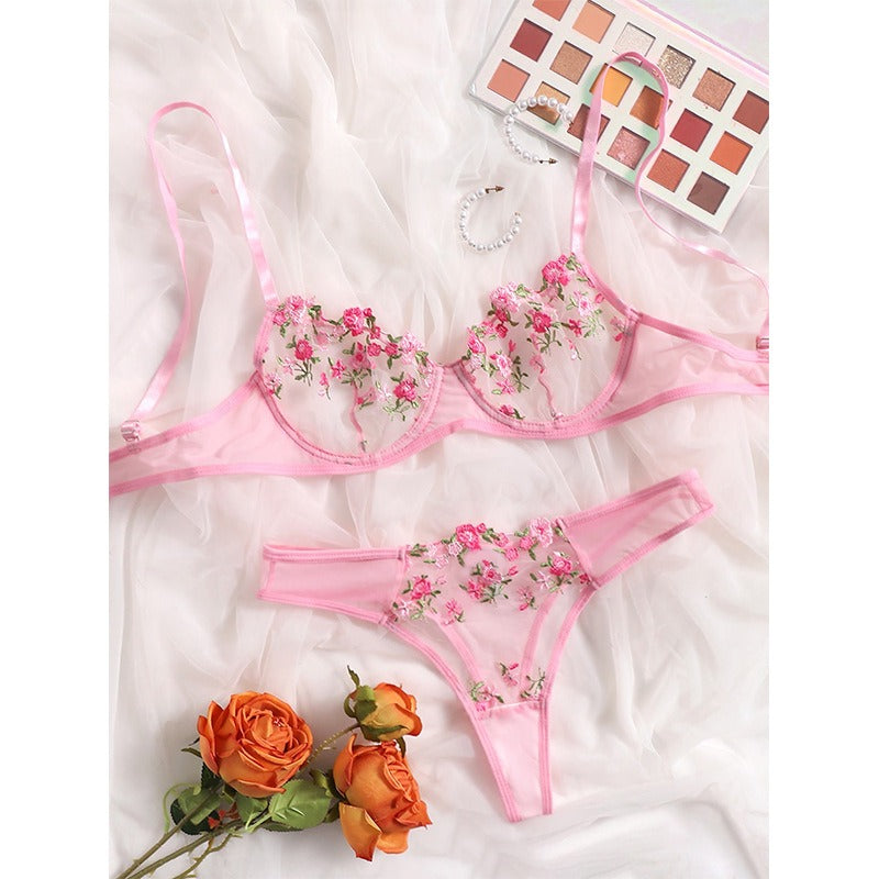 Pink floral lace lingerie set with embroidered flowers displayed on white fabric
