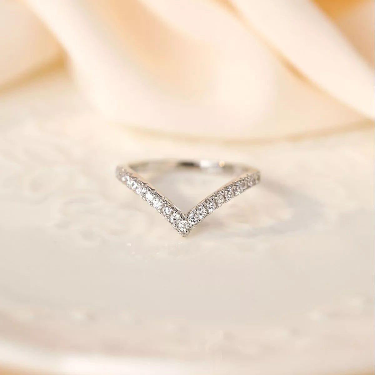 Front view of a V-shaped sterling silver ring with pavé-set diamonds