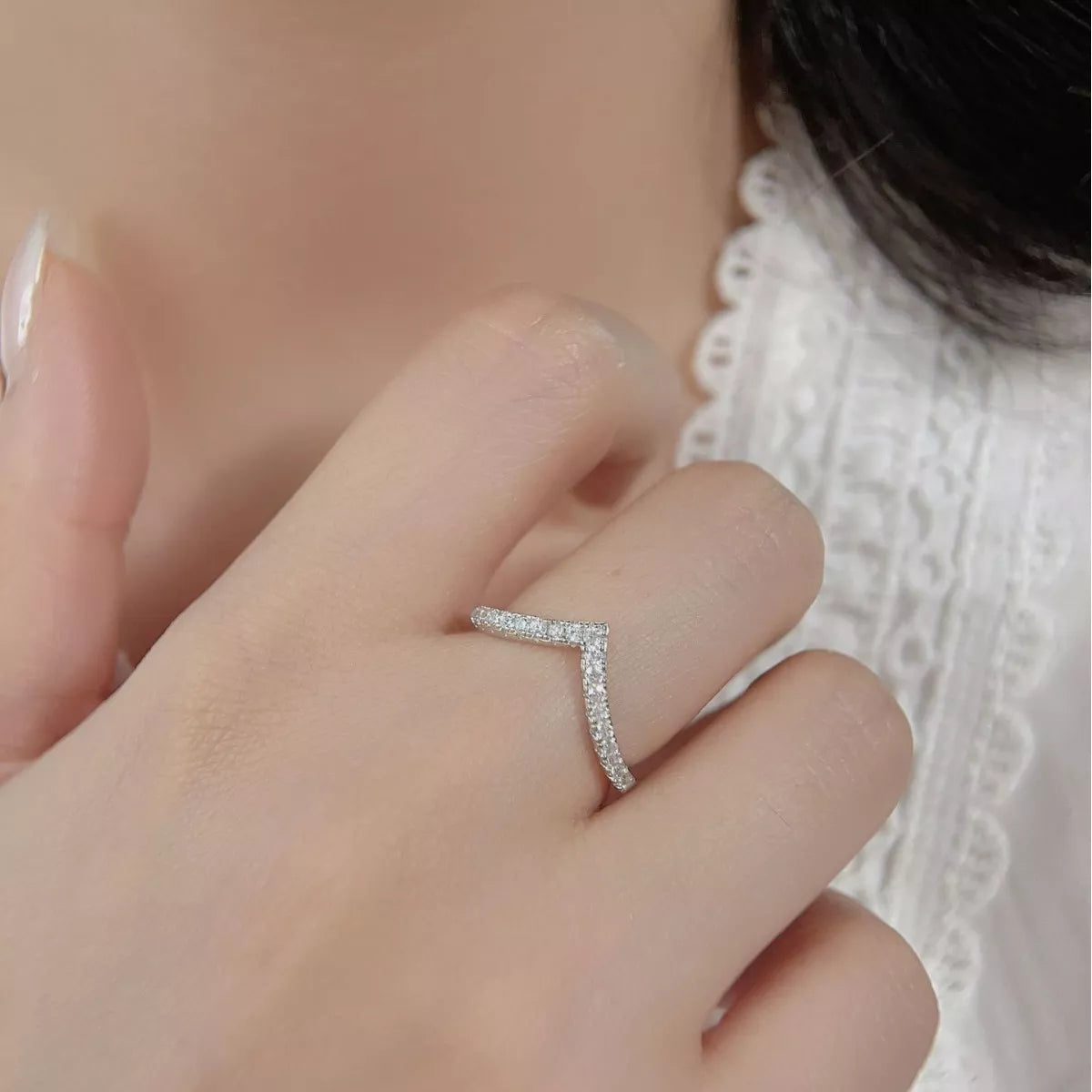 Close-up of V-shaped silver ring with small diamonds worn on hand