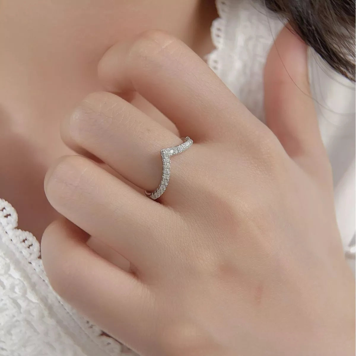 V-shaped silver ring with small diamonds worn on hand