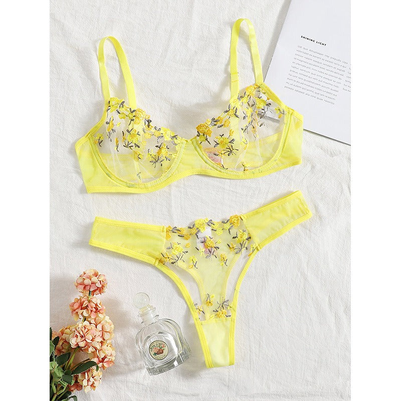 Yellow floral lace lingerie set with embroidered flowers displayed on a white fabric